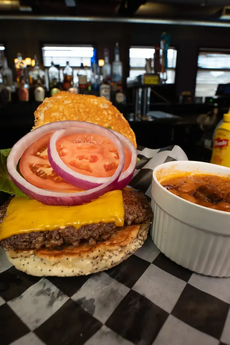 A Classic burger with American cheese, tomato and red onion, with baked beans A Classic burger with American cheese, tomato and red onion, with baked beans