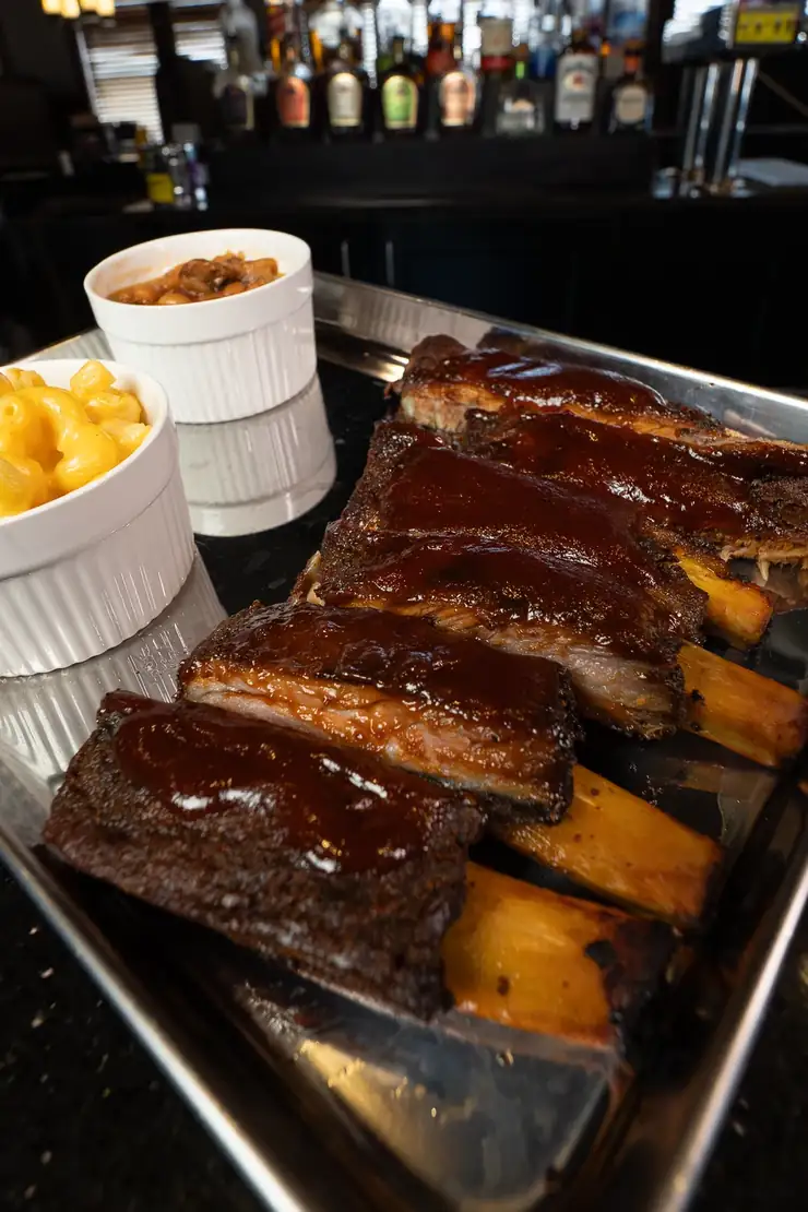 A tray of house smoked ribs with mac and cheese and baked beans A tray of house smoked ribs with mac and cheese and baked beans